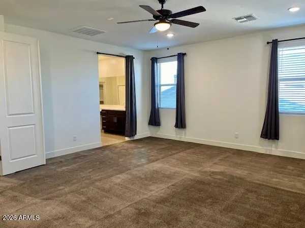 a view of an empty room with window and chandelier fan