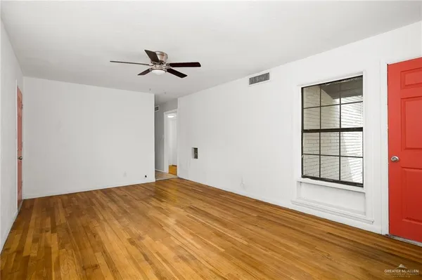 a view of empty room with wooden floor and fan