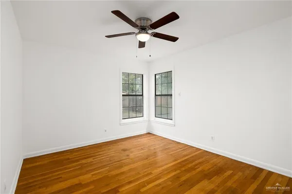 an empty room with wooden floor and ceiling fan