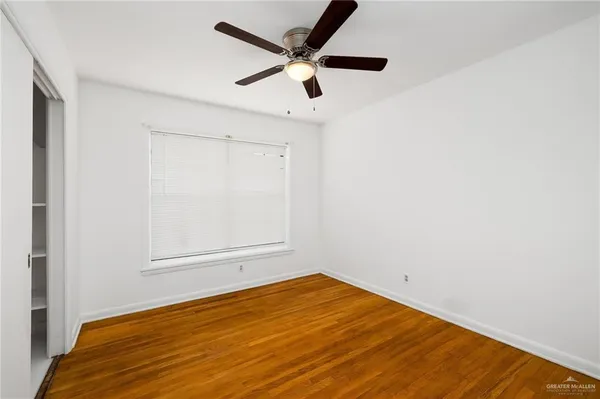 an empty room with a ceiling fan and wooden floor