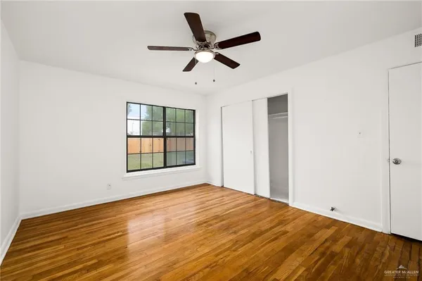 a view of an empty room with wooden floor and a window