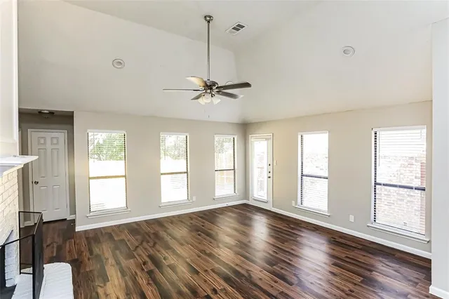 a view of an empty room with a window and wooden floor