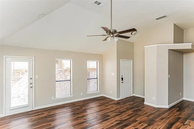 a view of empty room with wooden floor and fan