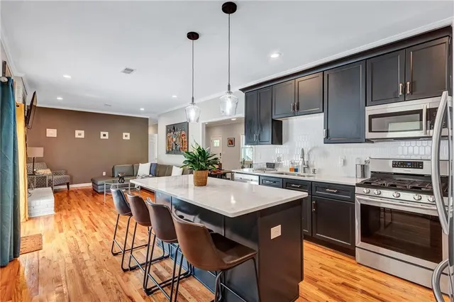 a kitchen with stainless steel appliances granite countertop a stove top oven a sink dishwasher a dining table and chairs with wooden floor