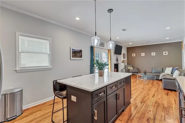 a view of a kitchen with kitchen island a island a sink a stove and wooden floor