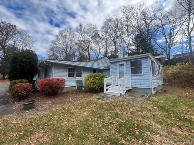 a view of a house with a yard and a large tree