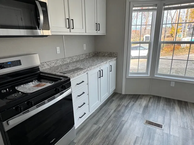 a view of a kitchen with wooden floor and a refrigerator