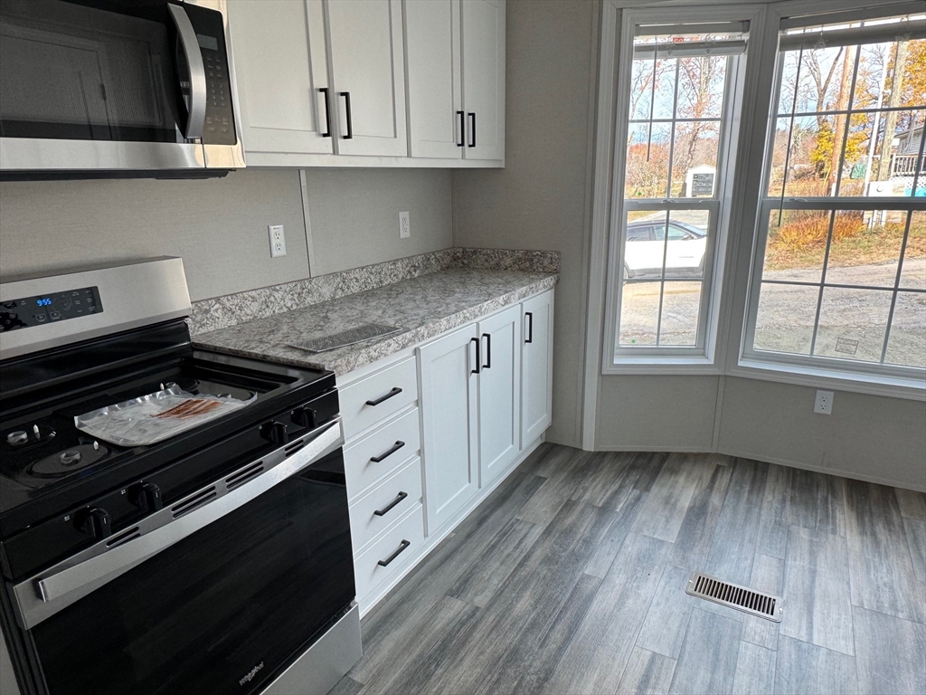 602 Fitchburg Road, Unit 19 Greenville, NH 03048 - Photo 8 of 14 a kitchen with granite countertop wooden cabinets and a stove top oven