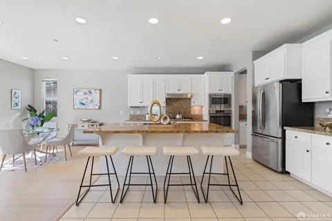 a kitchen with stainless steel appliances kitchen island granite countertop a refrigerator and cabinets
