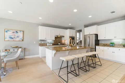 a kitchen with stainless steel appliances granite countertop a stove a sink a refrigerator a stove a dining table and chairs