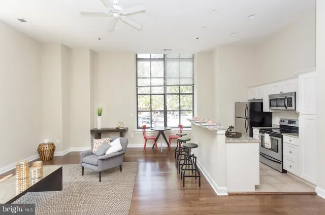 a living room with furniture large window and wooden floor