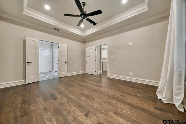 an empty room with wooden floor and ceiling fan