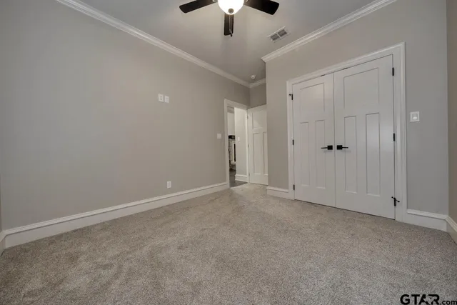 a view of an empty room and chandelier fan