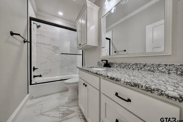 a bathroom with a granite countertop sink a toilet and shower