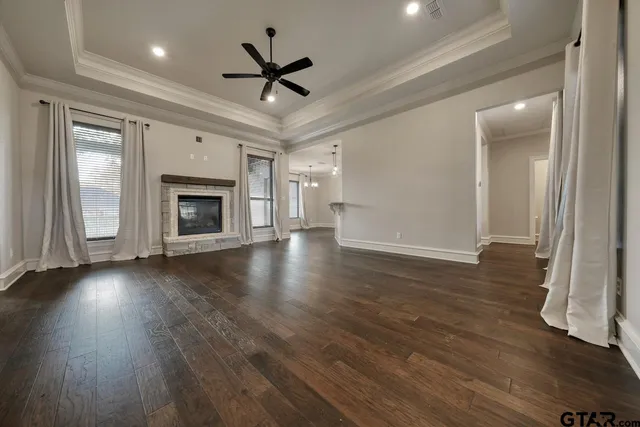 a view of an empty room with wooden floor fireplace and a window