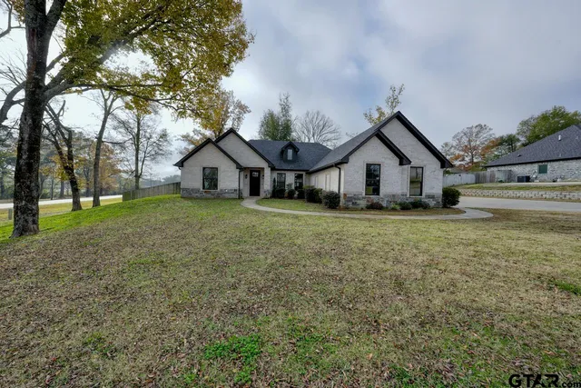 a view of a house with a yard and large trees