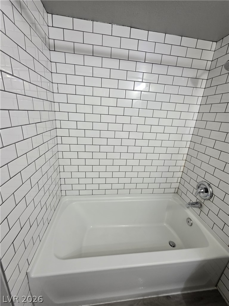 1089 East Desert Inn Road, Unit 3 Las Vegas, NV 89109 - Photo 7 of 15 A pristine bathtub with sleek subway tile surround creates a refreshing oasis.