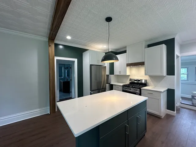 a large kitchen with sink a refrigerator and chairs