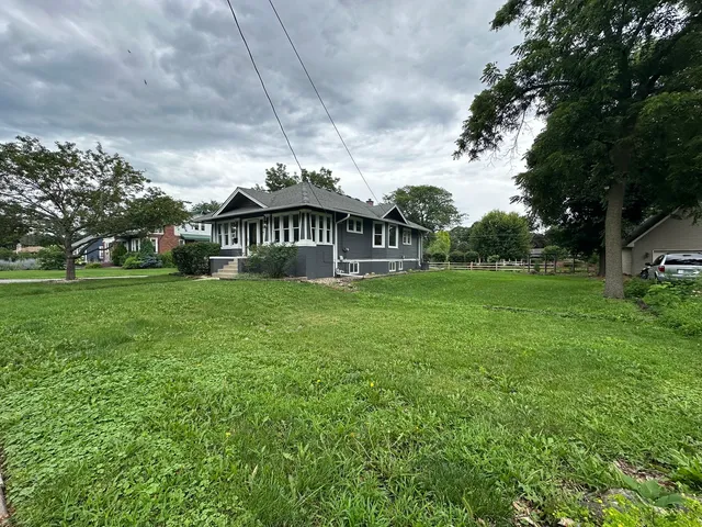 a view of a house with a big yard and large trees