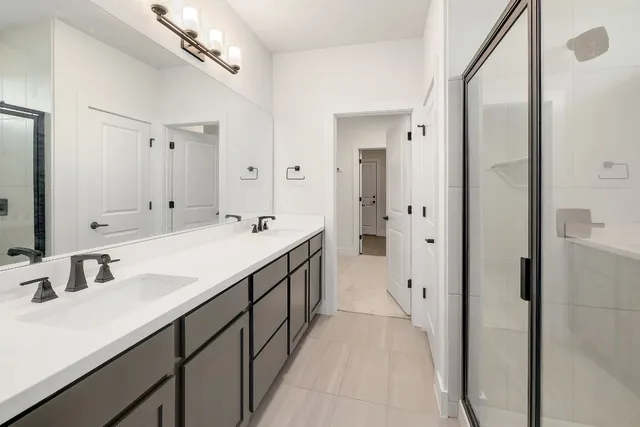 a spacious bathroom with a double vanity sink a mirror and a shower