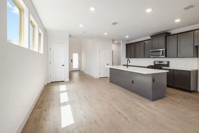 a open kitchen with kitchen island a sink dishwasher a refrigerator and a oven with wooden cabinets