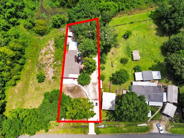 an aerial view of residential houses with outdoor space and trees all around