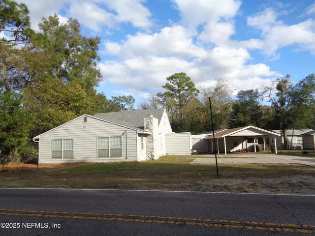 a view of a white house with a white door and a yard