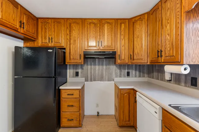 a kitchen with stainless steel appliances granite countertop a refrigerator a stove top oven and a refrigerator with wooden floor