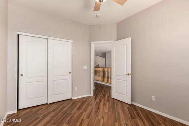 an empty room with wooden floor and a ceiling fan