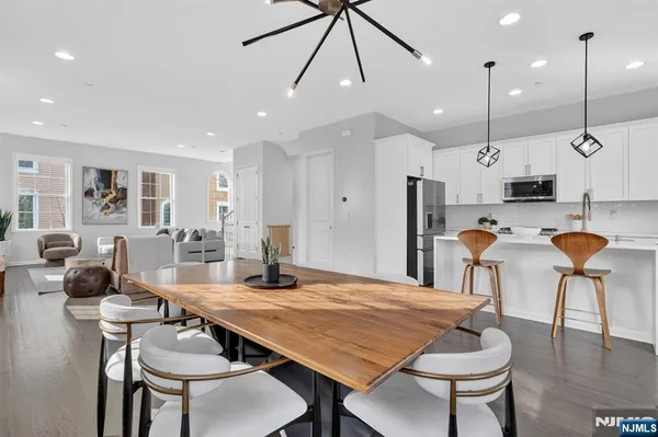 a kitchen with stainless steel appliances kitchen island granite countertop a table chairs and a refrigerator