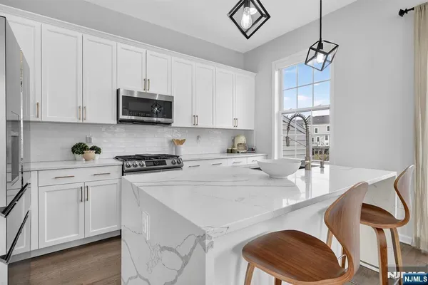a kitchen with stainless steel appliances granite countertop a stove a sink dishwasher and a refrigerator with white cabinets