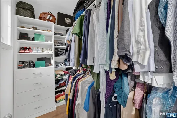 a view of walk in closet with clothes and shoes