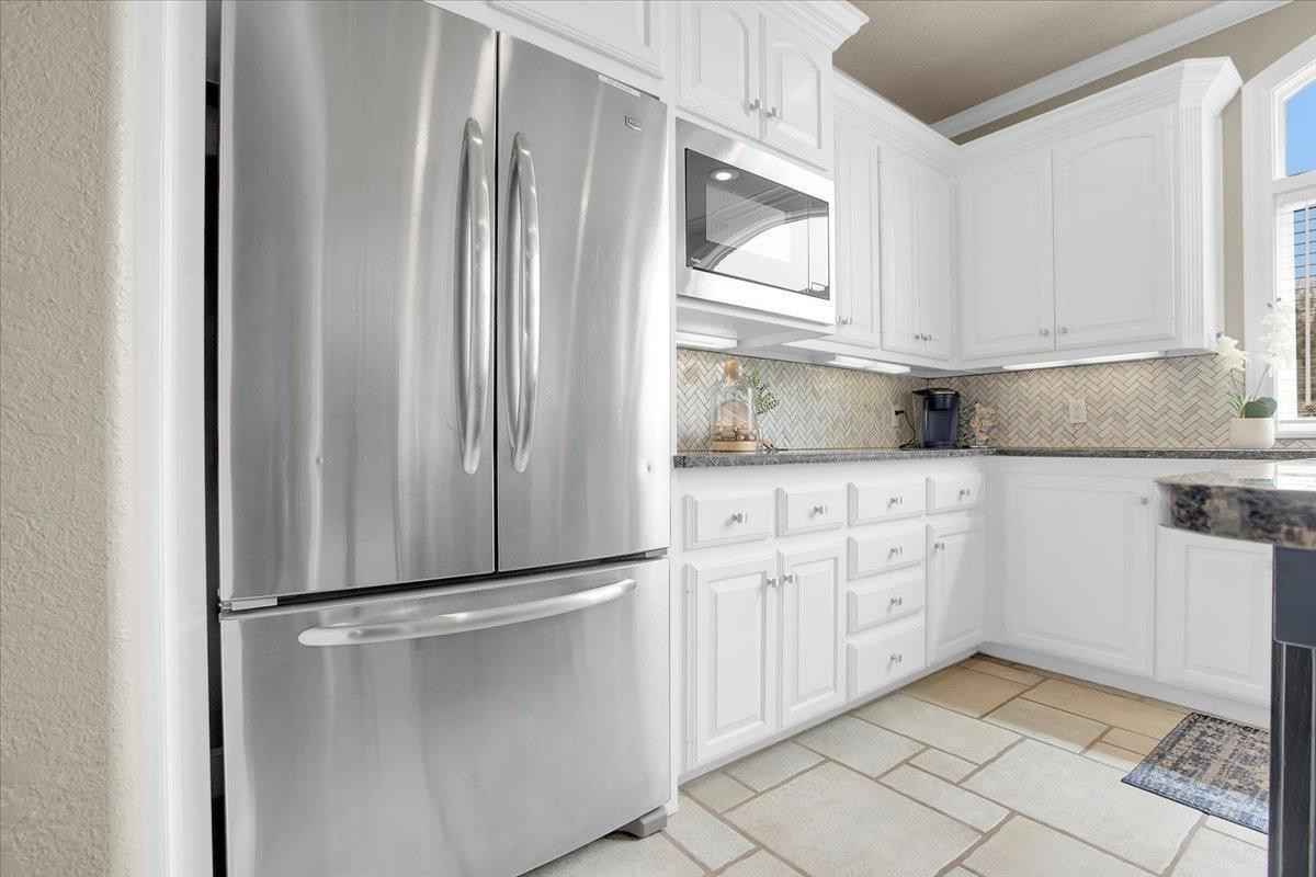 4818 104th Street Lubbock, TX 79424 - Photo 15 of 36 a kitchen with granite countertop a refrigerator and white cabinets