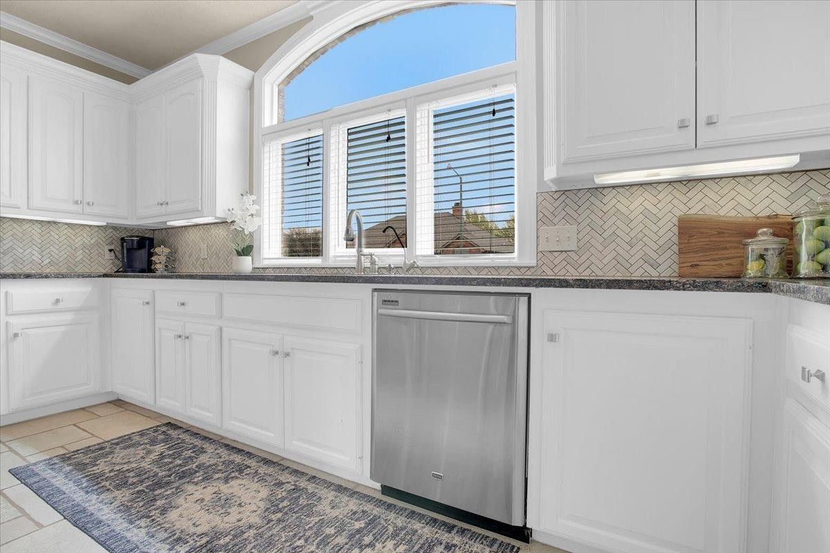 4818 104th Street Lubbock, TX 79424 - Photo 16 of 36 a kitchen with granite countertop white cabinets and a window