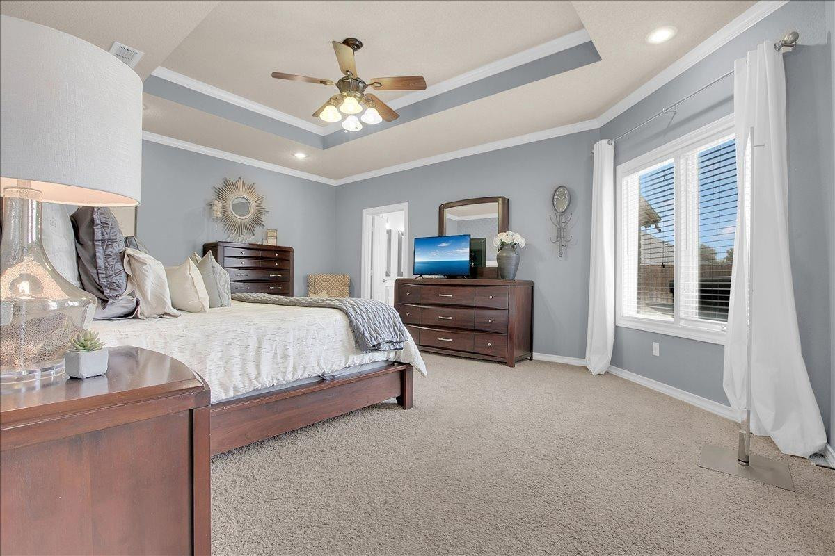 4818 104th Street Lubbock, TX 79424 - Photo 18 of 36 a spacious bedroom with a bed a chandelier and dresser