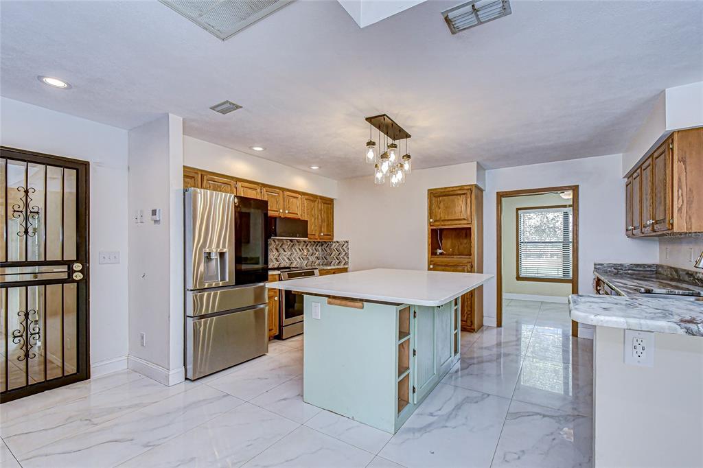 16349 Spring Valley Road Dade City, FL 33523 - Photo 19 of 40 a kitchen with kitchen island stainless steel appliances a sink stove and refrigerator