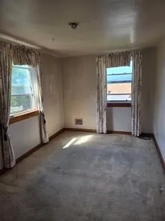 an empty room with a fireplace and windows