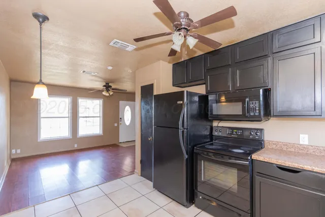 a kitchen with stainless steel appliances granite countertop a refrigerator a stove and a sink with wooden floors