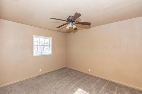 an empty room with a window and a fan