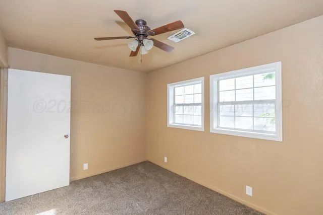 a view of a big room with a ceiling fan and windows