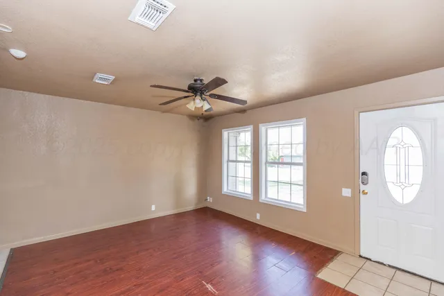 a view of an empty room with a window and wooden floor