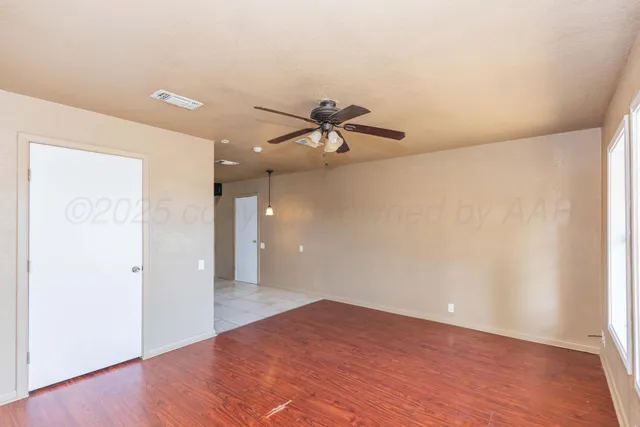 a view of a room with wooden floor and a ceiling fan