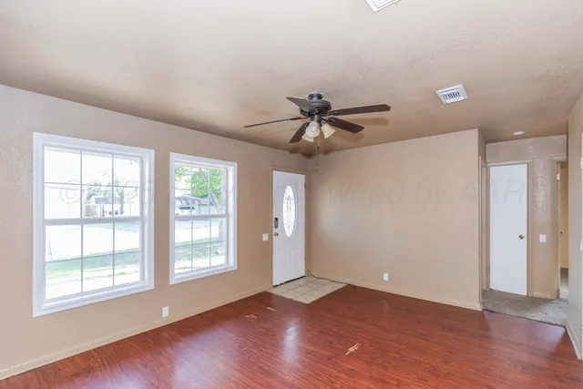 a view of an empty room with wooden floor and a window