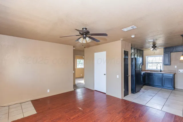 a view of an empty room and a kitchen