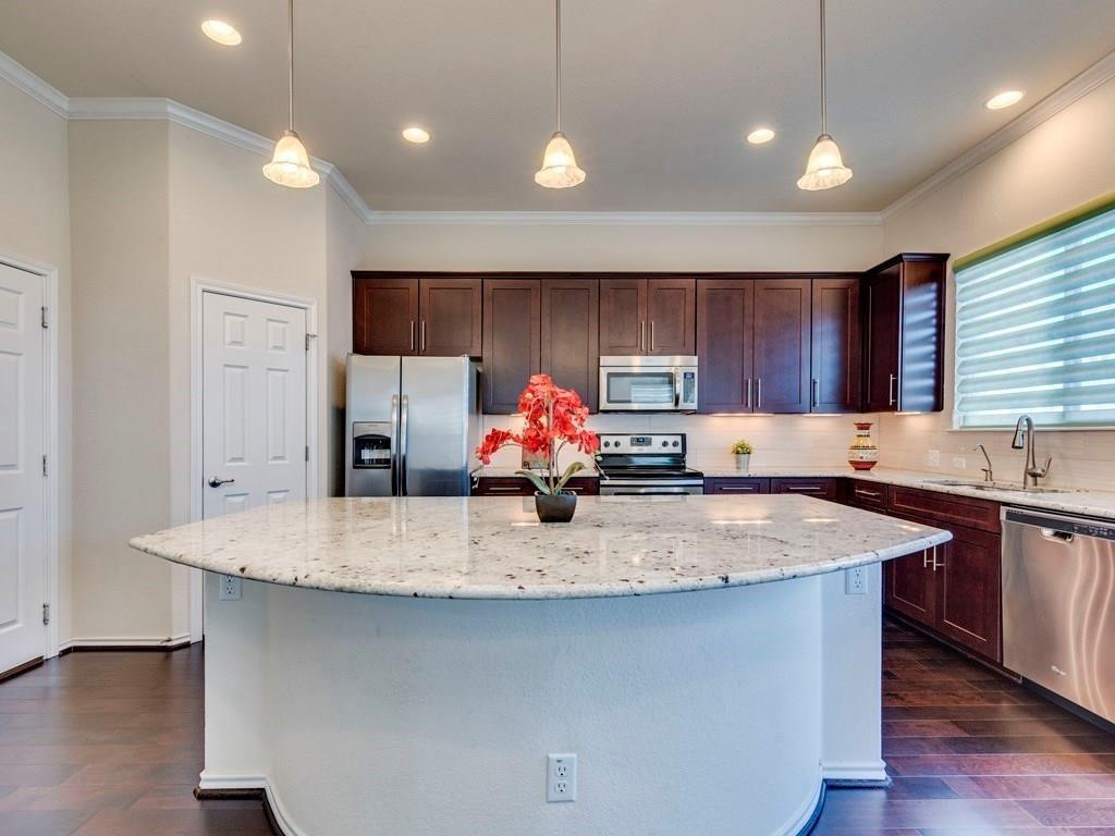 a kitchen with stainless steel appliances granite countertop a sink dishwasher and a stove with wooden floors