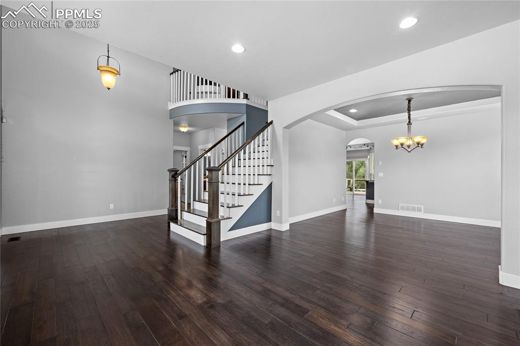 1069 Glengary Place Colorado Springs, CO 80921 - Photo 6 of 36 Living room with dark wood-type flooring, stairway, chandelier, recessed lighting, and arched walkways