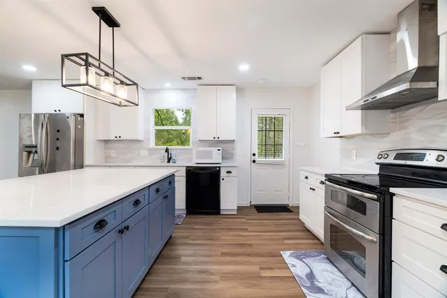 a kitchen with stainless steel appliances granite countertop a sink a stove and a refrigerator