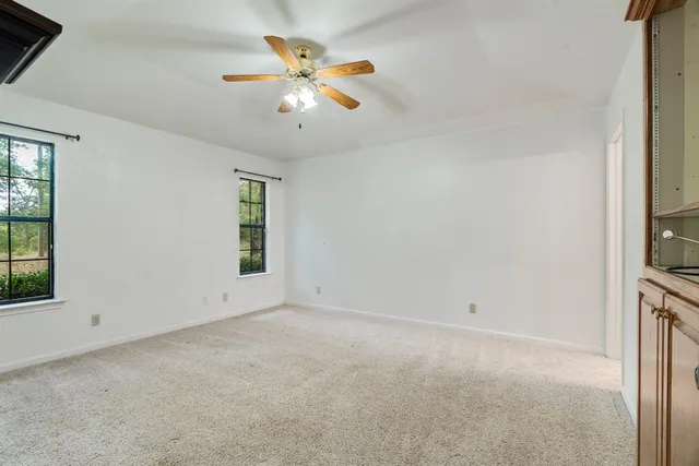 an empty room with windows and chandelier fan