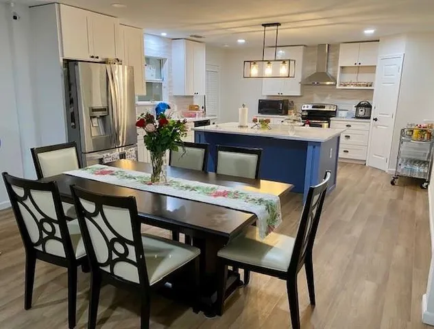 a kitchen with stainless steel appliances granite countertop a stove a refrigerator a kitchen island a table and chairs