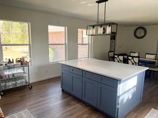 a kitchen with kitchen island granite countertop a stove a sink and a large refrigerator with wooden floor